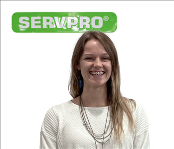 female employee in white sweater; green SERVPRO sign